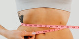 close-up of a pink soft tape measure held around a woman's waist