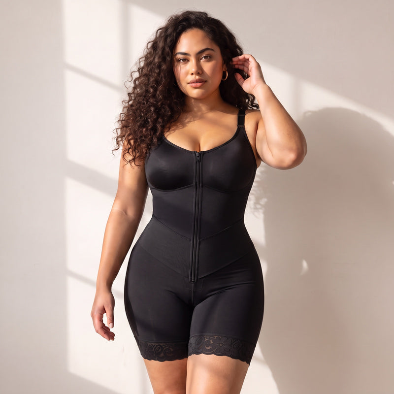 Woman wearing a black full bodysuit against a light wall in window light